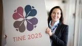 Dame i TINE holder opp skilt med TINE 2025. Les mer om TINE sin visjon og strategi her, frem mot 2025
