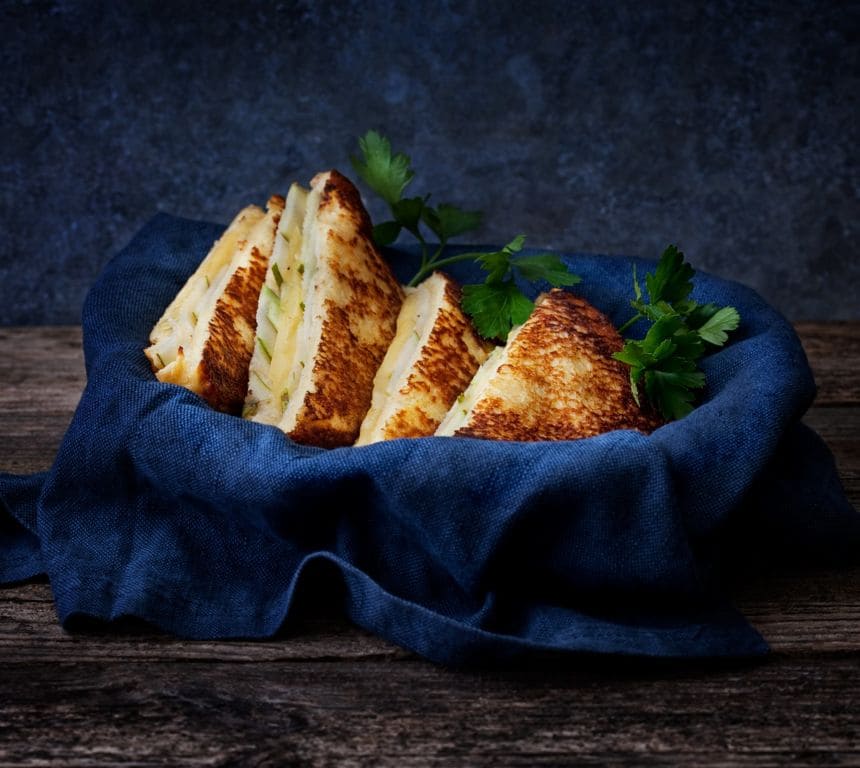 Bildet viser en toast med tre brødskiver. Mellom skivene er det avokado, spinat, pesto og ost som gjør at toasten ser grønn ut i utseende.