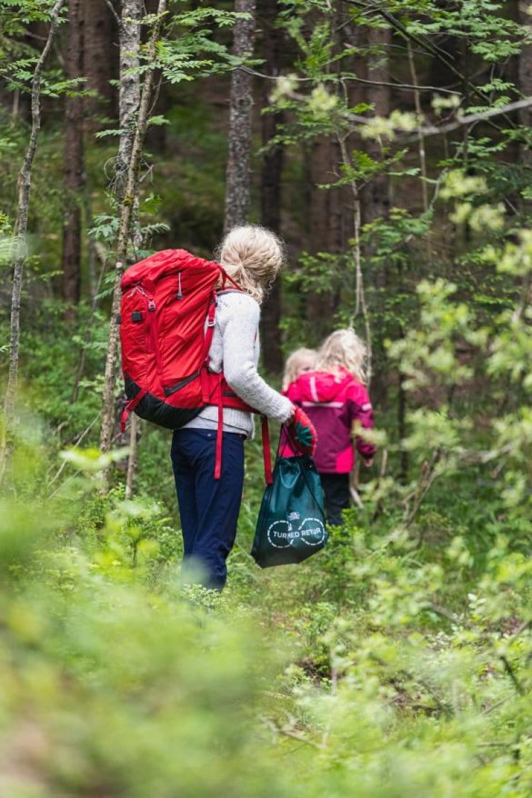 Mor med 2 døtre som går tur i skogen
