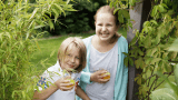 To barn som drikker juice i naturen