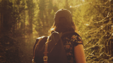 Jente med ryggsekk går tur i skogen