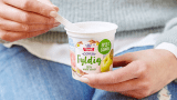 Kvinne spiser TINE Yoghurt Fyldig Eple & Guava