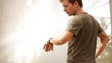 Mann ser på pulsklokken under trening i skogen