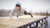 Mann tar push-ups med en arm på ryggen ute på en brygge