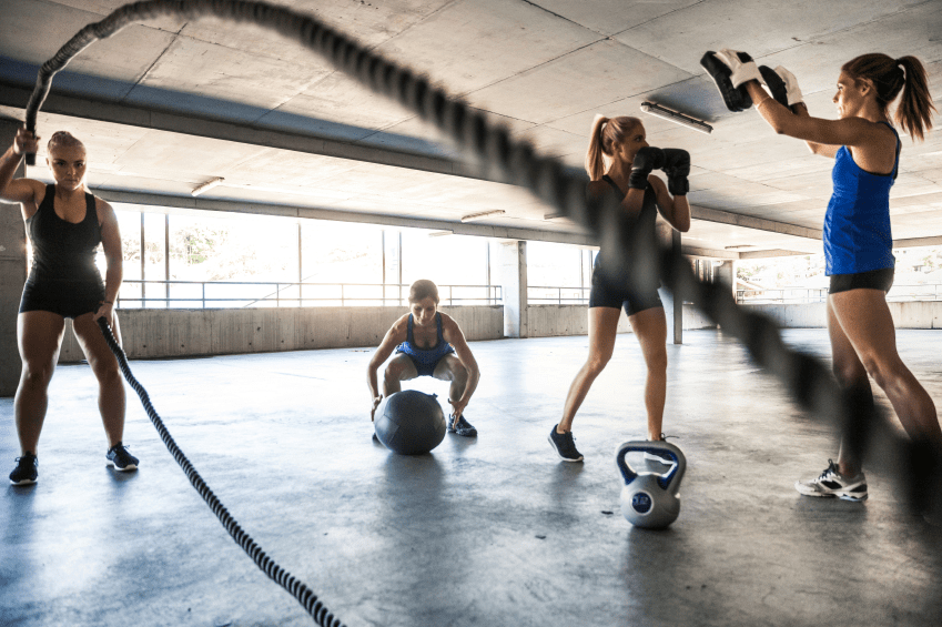 Gruppe mennesker trener sammen med hoppetau, boksehansker og kettlebells