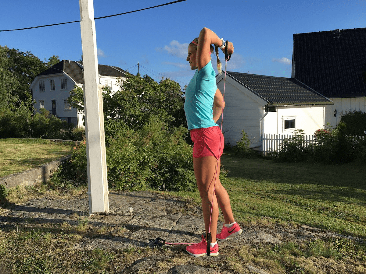 Kvinne gjør stående tricepspress med strikk