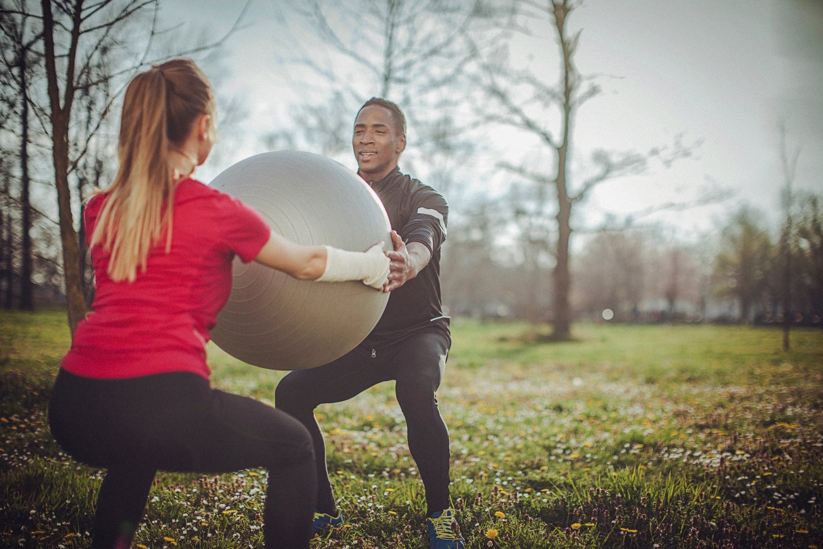 Mann og dame trener sammen med stor ball utendørs