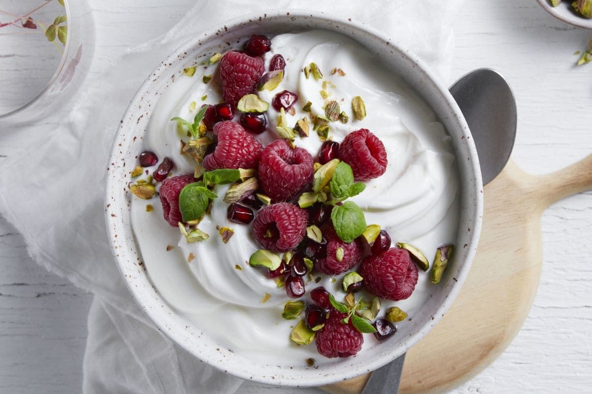 Proteinfrokost med gresk type yoghurt, friske bringebær, granateple og pistasjnøtter